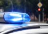 Blue police siren light flashing on vehicle roof.
