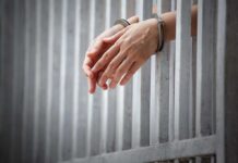 Hands in handcuffs through jail bars