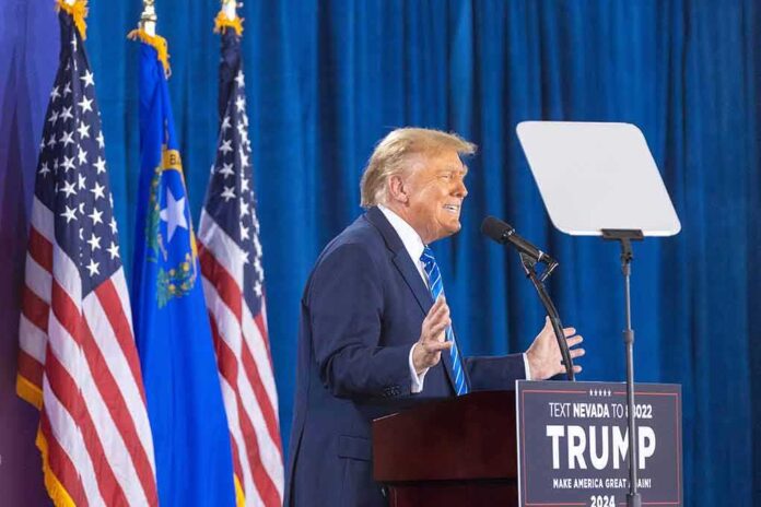 2427935455 featured image Person speaking at podium with flags in background.
