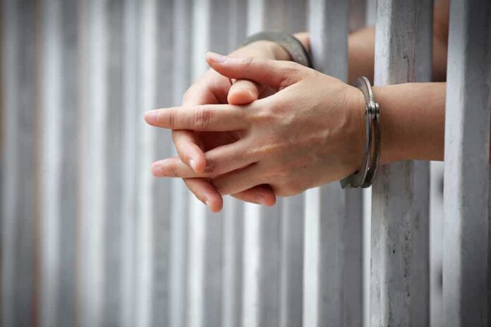 1031018551 featured image Hands in handcuffs gripping prison bars