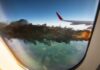 Airplane wing with engine on fire mid-flight.