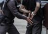 Police officer arrests person in handcuffs outdoors