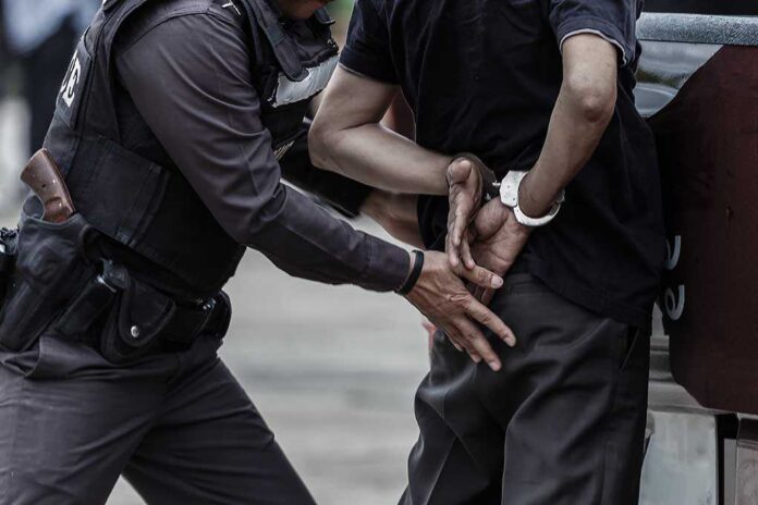 665013085 featured image Police officer arrests person in handcuffs outdoors