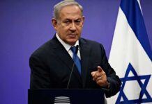 Man in suit giving speech in front of Israeli flag