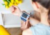 Person checking wrist blood pressure monitor indoors