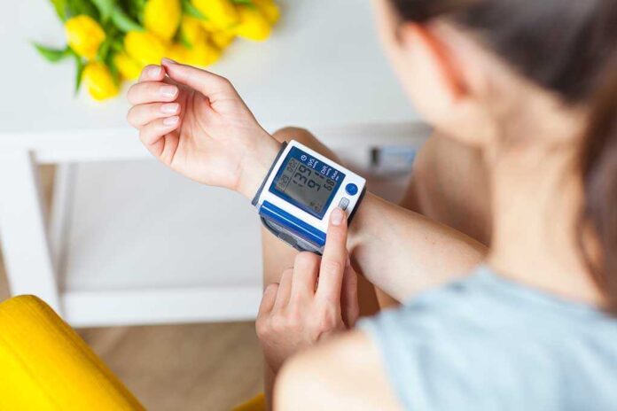 1078631948 featured image Person checking wrist blood pressure monitor indoors