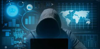 Hacker in hoodie using laptop with digital graphs