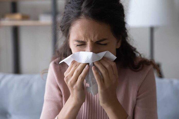 1906128409 featured image Woman sneezing into a tissue indoors