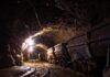 Dimly lit mine shaft with rail carts and tracks.