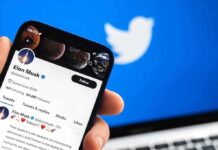 Hand holding phone displaying Twitter profile