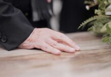 Hand on table beside floral arrangement