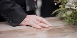 Hand on table beside floral arrangement