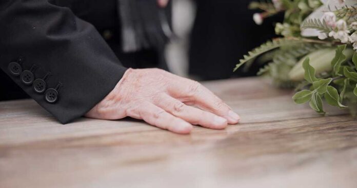 2352932431 featured image Hand on table beside floral arrangement