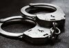 Close-up of metal handcuffs on a dark surface.