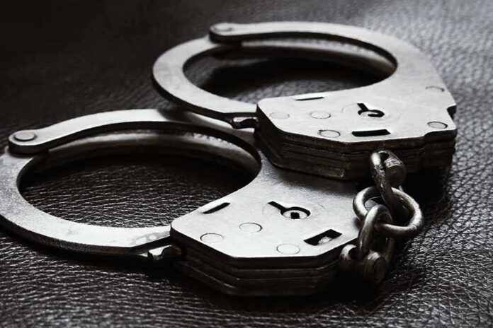 Close-up of metal handcuffs on a dark surface.
