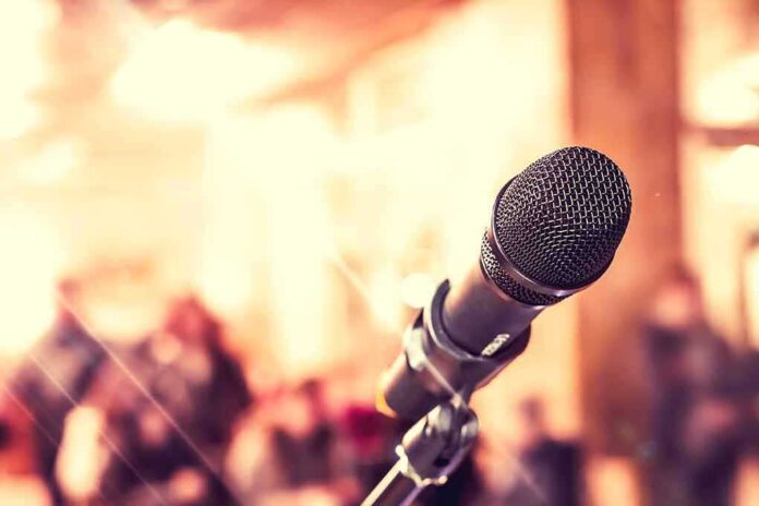 347902208 featured image Closeup of microphone with blurred audience background