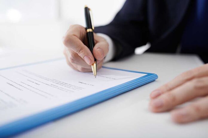 Person signing a document with a pen