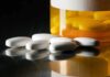 White pills beside an orange pill bottle