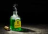 Green poison bottle with cork on wooden surface