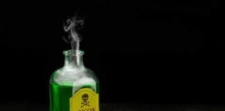 Green poison bottle with cork on wooden surface