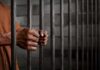 Hands gripping prison cell bars