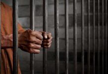 Hands gripping prison cell bars