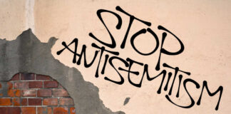 Stop antisemitism graffiti on a worn brick wall