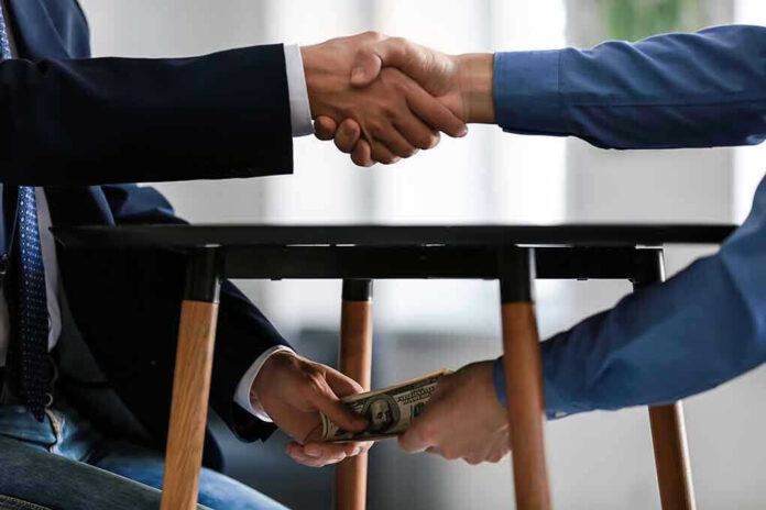 1225177960 Handshake and exchange of money under the table