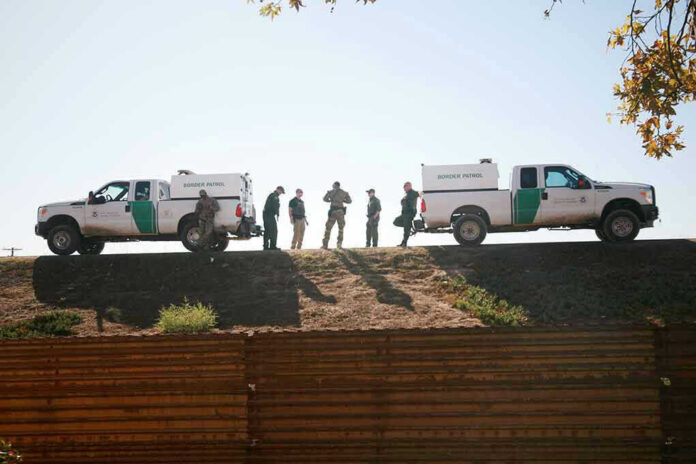 1243518340 Border Patrol vehicles and agents on a ridge