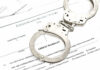 Handcuffs on top of an arrest warrant document