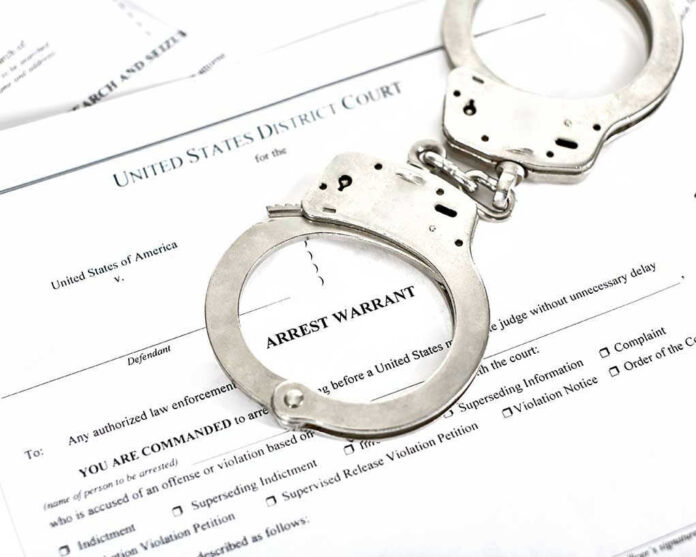 1316784506 Handcuffs on top of an arrest warrant document