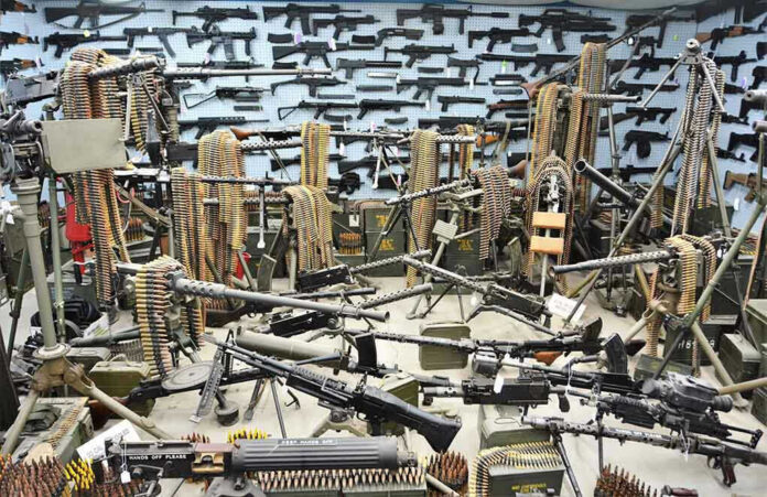 1967096365 Room filled with various firearms and ammunition belts