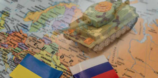 Toy tank on map with Ukraine and Russia flags.