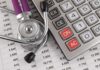 A stethoscope resting on a calculator and financial data sheets
