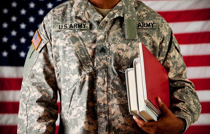 shutterstock_184208507.jpg A soldier in a US Army uniform holding books in front of an American flag