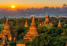 Sunset over ancient temple complex with lush greenery