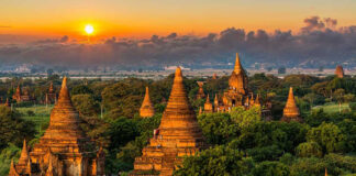 Sunset over ancient temple complex with lush greenery