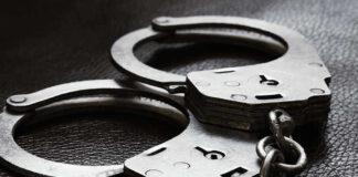 Close-up of metal handcuffs on a dark surface.