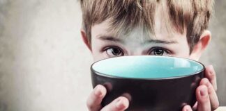 A child with a serious expression holding a bowl close to their face