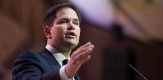 A man in a suit delivering a speech at a podium