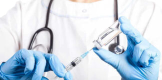 Doctor filling syringe with vaccine from vial