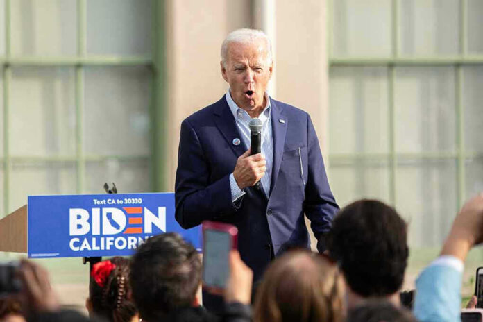 Man speaking at an outdoor event with Biden sign