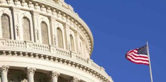 Close up of the US Capitol building with an American flag waving in the foreground