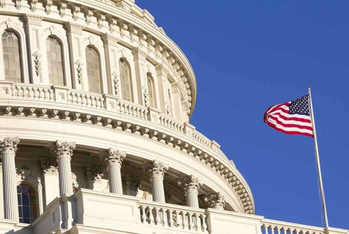 Close up of the US Capitol building with an American flag waving in the foreground