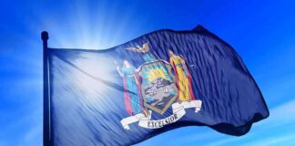 New York state flag waving against a blue sky