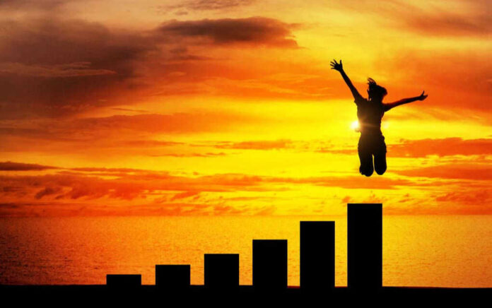 Silhouette jumping above bar chart at sunset.