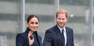 A couple dressed in formal attire smiling and walking hand in hand