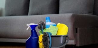 BRAIN Risk ALERT – Common CLEANERS Under Fire A bucket filled with various cleaning supplies including sponges, brushes, and spray bottles