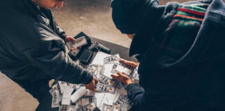 UNBELIEVABLE Pokémon Card Heist: BIZARRE METHODS Two individuals handling stacks of money on a table.