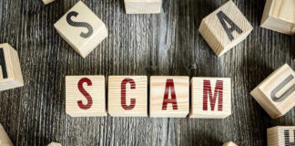 Trump KILLS $30 Billion Green Energy Scam Wooden blocks spell SCAM on a rustic surface.